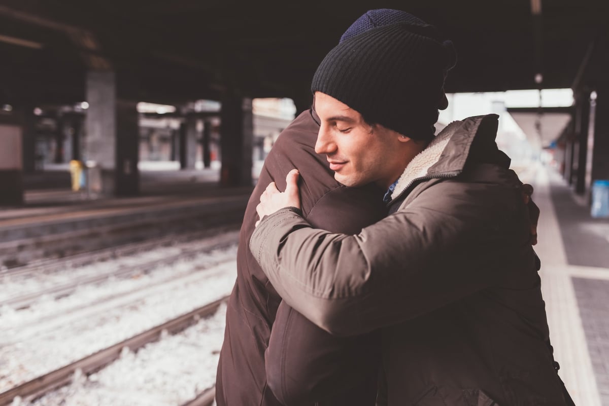 two-multiethnic-male-friends-standing-in-train-sta-2022-02-24-03-27-21-utc-scaled